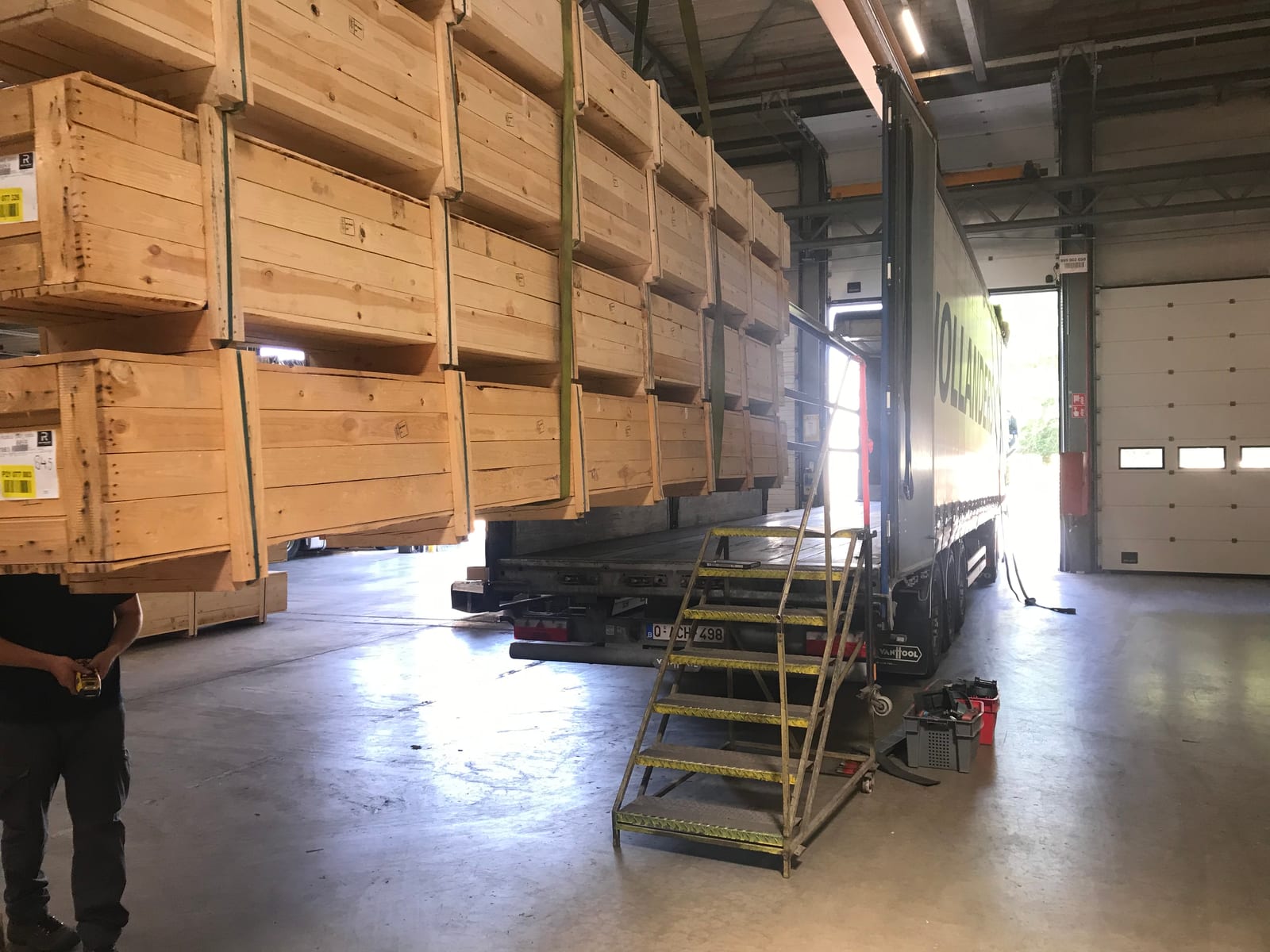 Houten kratten worden geladen op een schuifzeiltrailer van Hollanders Carl