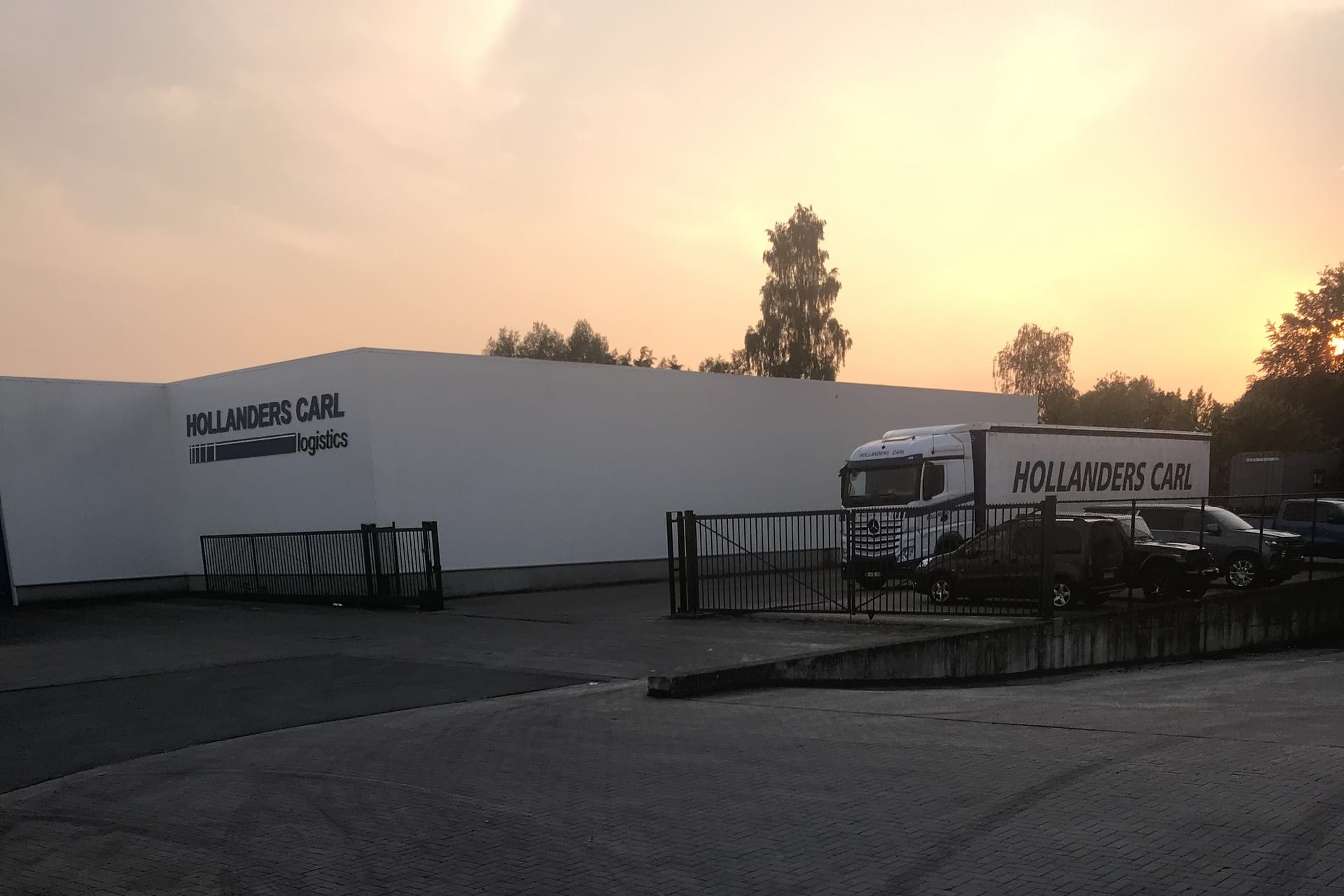 Hollanders Carl logistics warehouse and entrance gate in Stekene at sunset